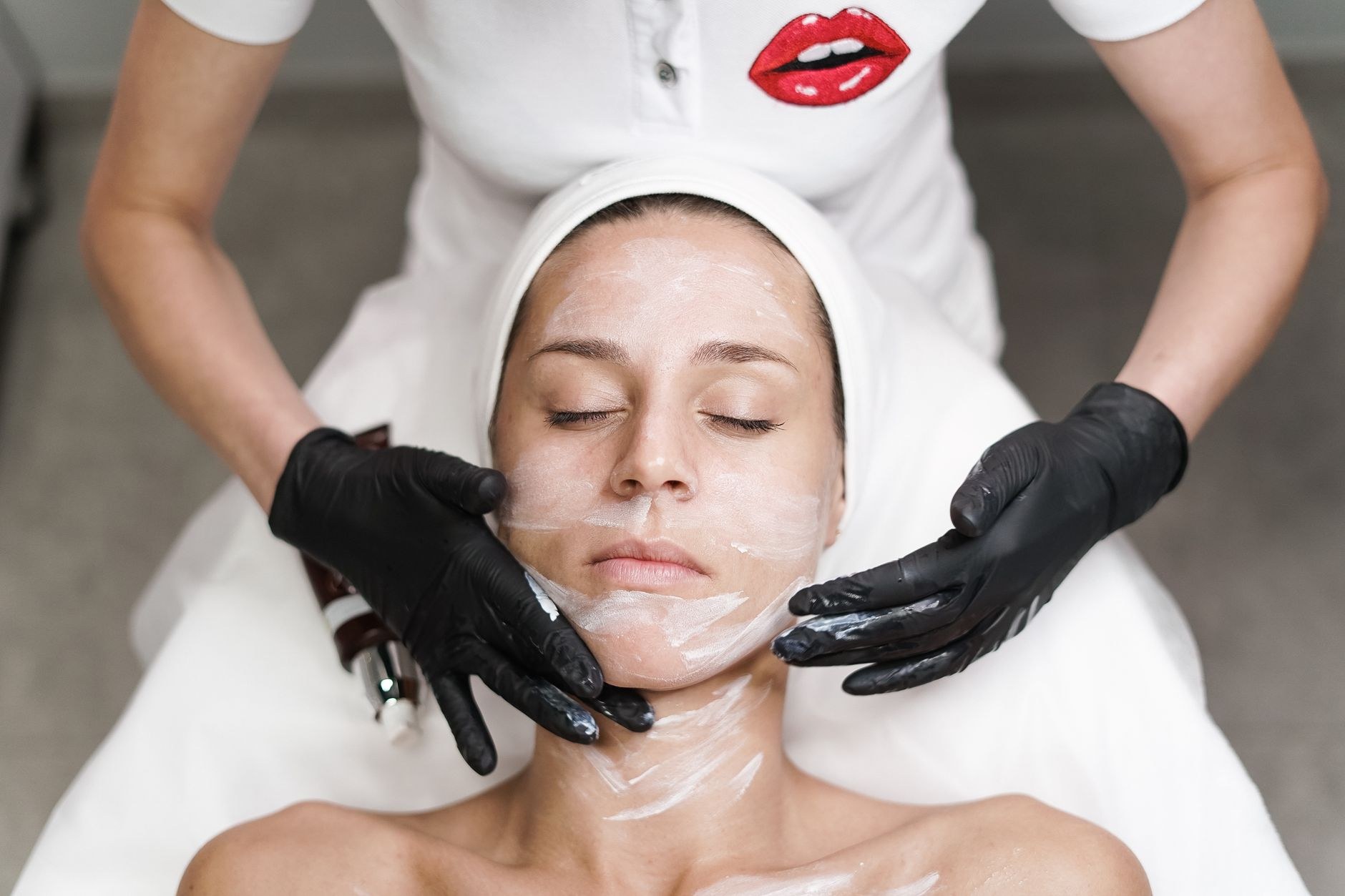 Facial treatment in progress: a therapist applying skincare to a relaxed client